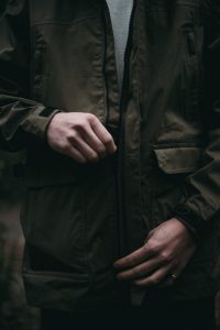 man zipping a green jacket