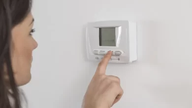 woman adjusting heating thermostat