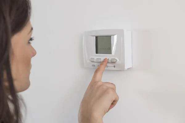 woman adjusting heating thermostat